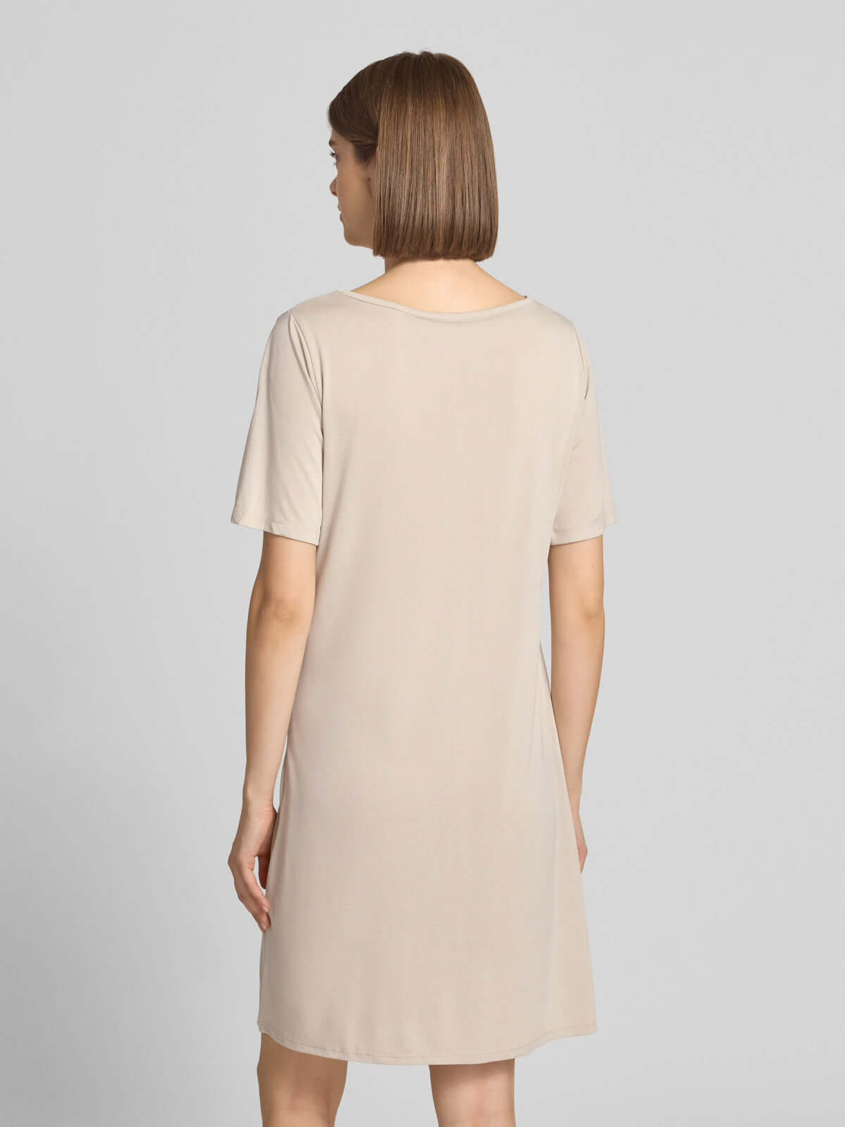 Back view of a woman wearing a beige Pieces Pcanora Short Dress, featuring short sleeves and a classic V-neckline.