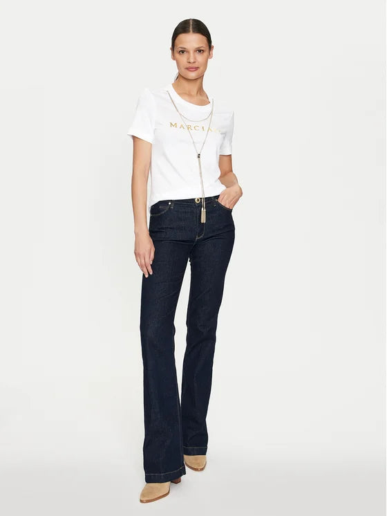 Model wearing Marciano Guess T-Shirt Olivia White Regular Fit with dark flared jeans, showcasing women's fashion and premium brands.