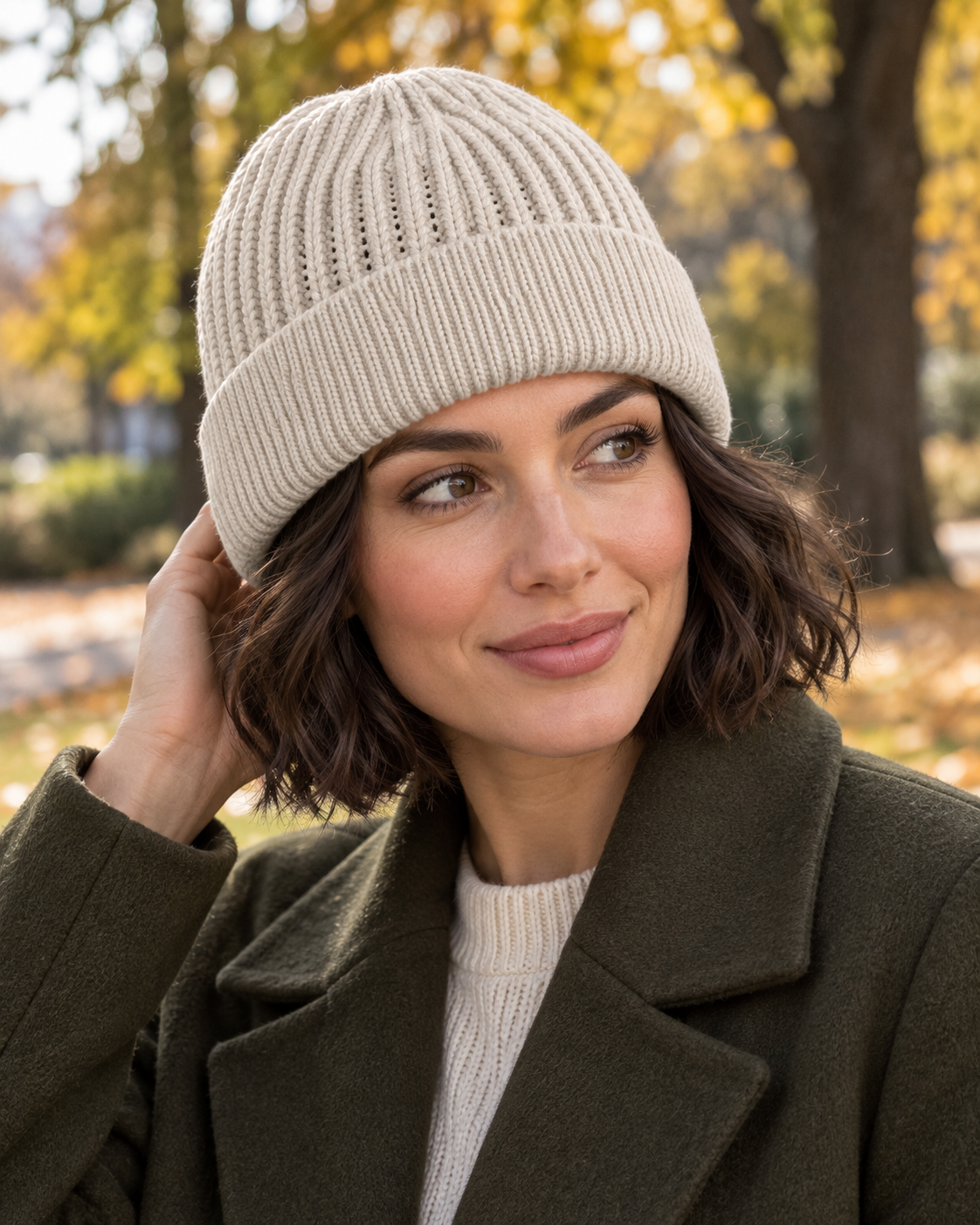 Woman wearing the light beige s.Oliver textured beanie with an olive coat during an autumn park walk.